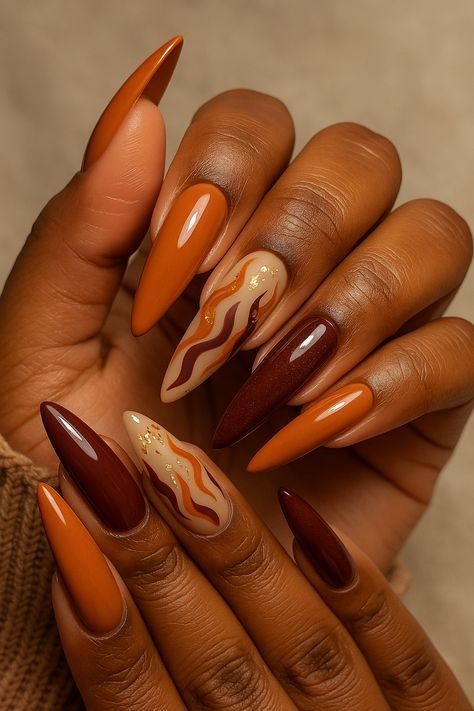 Burnt orange and chocolate brown stiletto nails on dark skin with swirl art accent nails