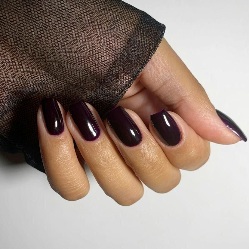 Deep plum short square nails in a glossy near black purple gel with a sheer black sleeve
