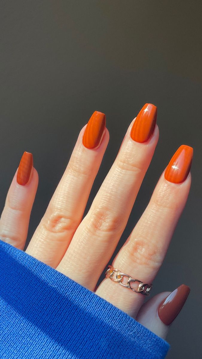 Bright pumpkin orange almond nails, vivid glossy orange gel with one burgundy accent nail