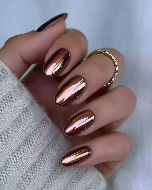 Copper brown chrome almond nails with a mirror metallic finish reflecting pink and bronze light