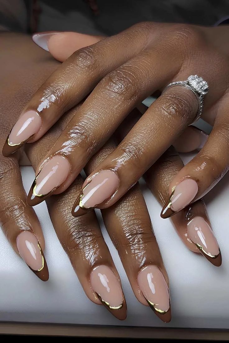 Nude almond nails with gold tips on dark skin, elegant neutral gel set with fine gold edging